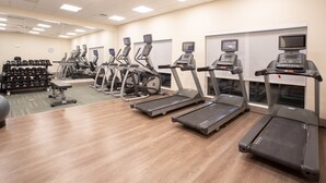 Une salle de sport équipée de tapis de course, de vélos elliptiques et de poids libres.
