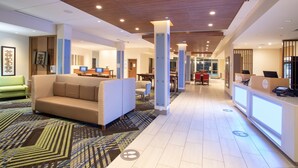 Un hall d’hôtel comprenant un comptoir d’accueil, un espace salon et un tapis à motifs.