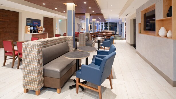 Un hall d’hôtel moderne, doté d’espaces de détente, d’un coin café et offrant une vue sur la salle à manger.