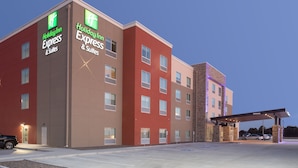 Un bâtiment de l’hôtel Holiday Inn Express avec une façade rouge et beige, de nombreuses fenêtres et un espace de stationnement couvert.
