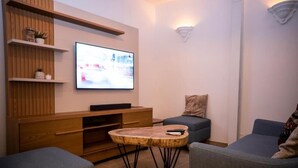 Ein modernes Wohnzimmer mit einem an der Wand befestigten Flachbildfernseher, einer Holzunterhaltungsecke und zwei grauen Sofas.