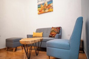 Un salon moderne avec un canapé bleu, une table basse en bois et un coussin aux couleurs vives.
