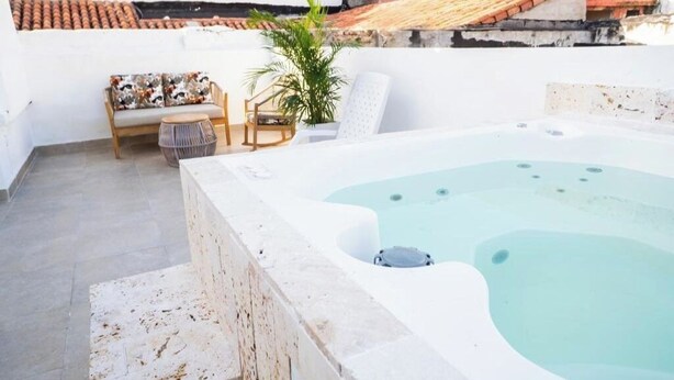 Eine Dachterrasse mit Whirlpool, Sitzgelegenheit und einem Blumentopf.