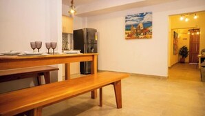 Ein Essbereich mit Holztisch und Bänken, einem K ühlschrank und einem Bild an der Wand.