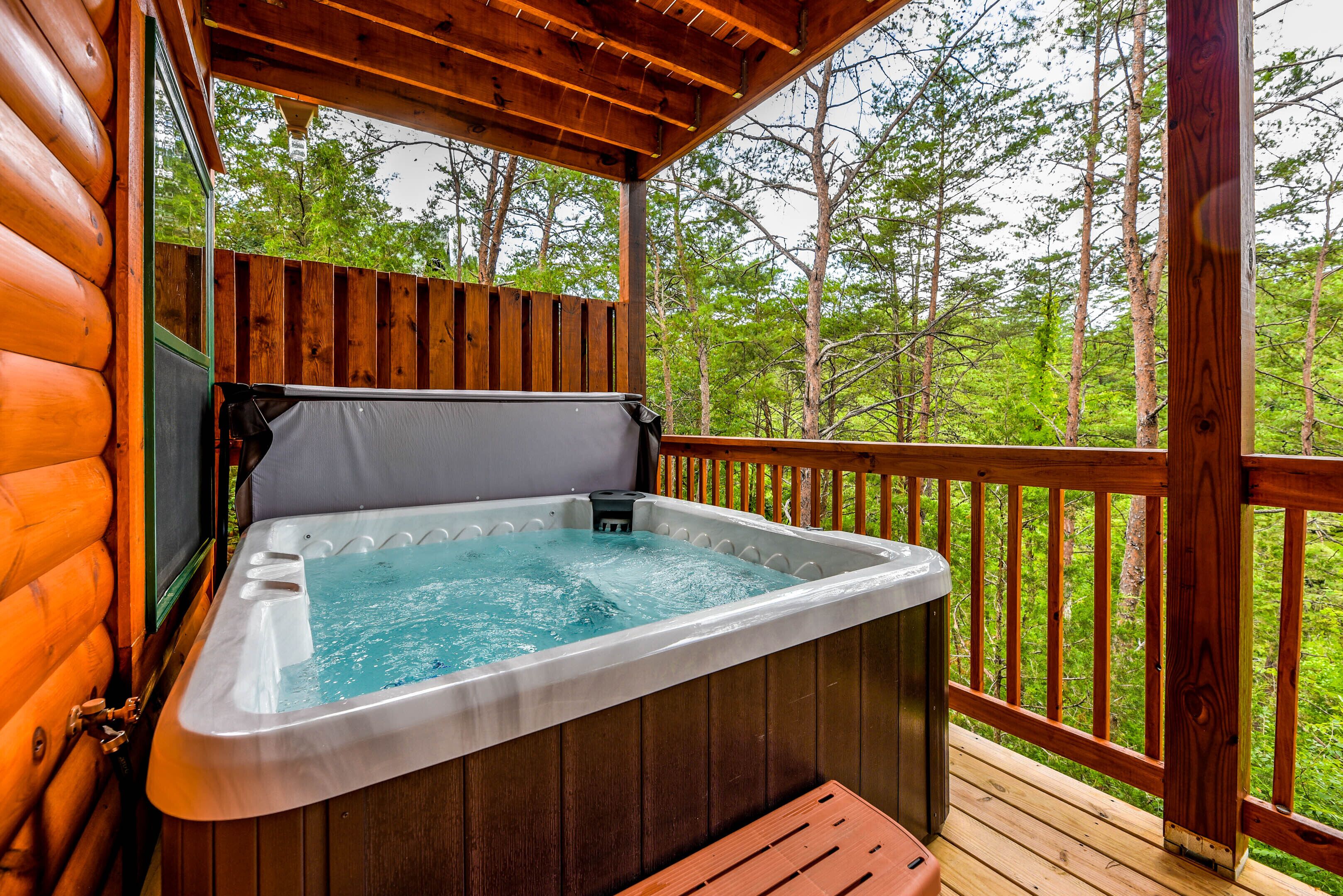 A hot tub on a wooden deck with a view of a forest.