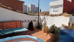 A rooftop terrace with a small inflatable pool, a bench, potted plants, and a view of the cityscape. - Village house with large terrace.  (Valencia)