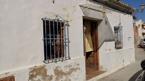 A white building with a wooden door and a window with metal bars. - Village house with large terrace.  (Valencia)
