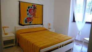 A bedroom with a bed, a nightstand, a lamp, and a window with curtains. - ARBACANI HOLIDAYS (Gallipoli)