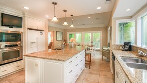 A modern kitchen with white cabinetry, granite countertops, stainless steel appliances, and pendant lighting. - DOG FRIENDLY Four Bedroom 3rd Row Ocean Sea Pines Home with a Private Pool (Hilton Head Island)