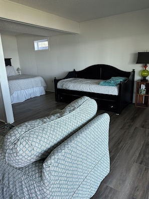 Une chambre à coucher avec un lit, une chaise, une table de chevet et une fenêtre.
