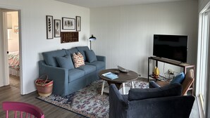 A living room with a grey sofa, a coffee table, a TV on a stand, and a patterned rug.