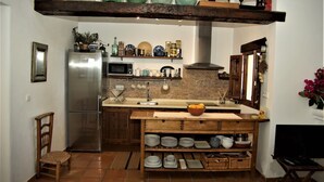 Een keuken met een houten kookeiland, roestvrijstalen apparatuur en planken met glaswerk.
