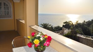 A balcony with a table and chairs, a vase of flowers, and a view of the sea. - Studio mit Pool Maria am Agios Gordios (Agios Gordios)
