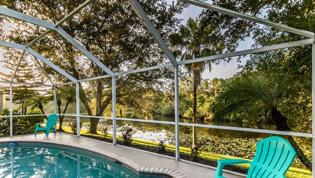An outdoor pool area with a clear view of a pond and surrounding greenery. - Jumpin Fish House 3BR/2BA Pool Home on the Canal (Sebastian)