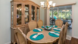 A dining room with a wooden cabinet, round table, and chairs. - Jumpin Fish House 3BR/2BA Pool Home on the Canal (Sebastian)