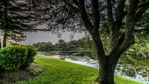 A serene park with a pond, lush green grass, and mature trees. - Jumpin Fish House 3BR/2BA Pool Home on the Canal (Sebastian)