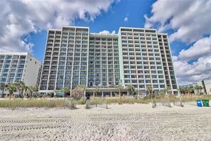 Un hôtel à plusieurs étages doté d’une architecture moderne, avec des balcons et une vue sur la plage.