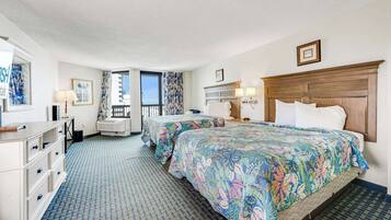 A hotel room with two beds, a dresser, a vanity, a window with a view, and a balcony.