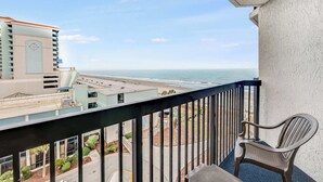 A balcony with a view of the ocean and a chair. - Oceanview Studio at Compass Cove with Pools,Updated! (Myrtle Beach)