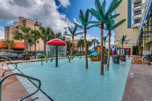 An indoor pool area with water slides and palm trees.
