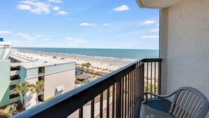 A balcony with a view of the beach and ocean.