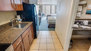 A compact kitchen with granite countertops, a sink, and wooden cabinets.