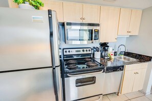 Une cuisine compacte équipée d’un réfrigérateur en acier inoxydable, d’un four à micro-ondes, d’une cuisinière et d’un lave-vaisselle.