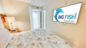Habitación de hotel con cama, mesita de noche, lámpara y un cartel en la pared de Big Fish Rentals.
