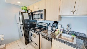 Una cocina moderna con electrodomésticos de acero inoxidable, encimera de granito y armarios de colores claros.