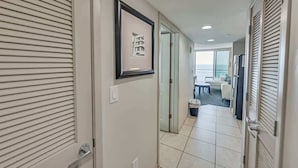 Ein Hotelgang mit einem gerahmten Bild an der Wand, ein Badezimmer mit Waschbecken und Spiegel sowie Meerblick durch das Fenster.