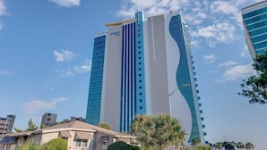 Ein hohes, modernes Hotel mit einer markanten, gebogenen Fassade und einem gut sichtbaren 'Ocean One' Schild.