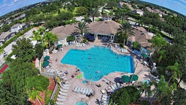 An aerial view of a resort with a large central pool surrounded by lounge chairs and palm trees. - Windsor_palms_303cp-n (Kissimmee)