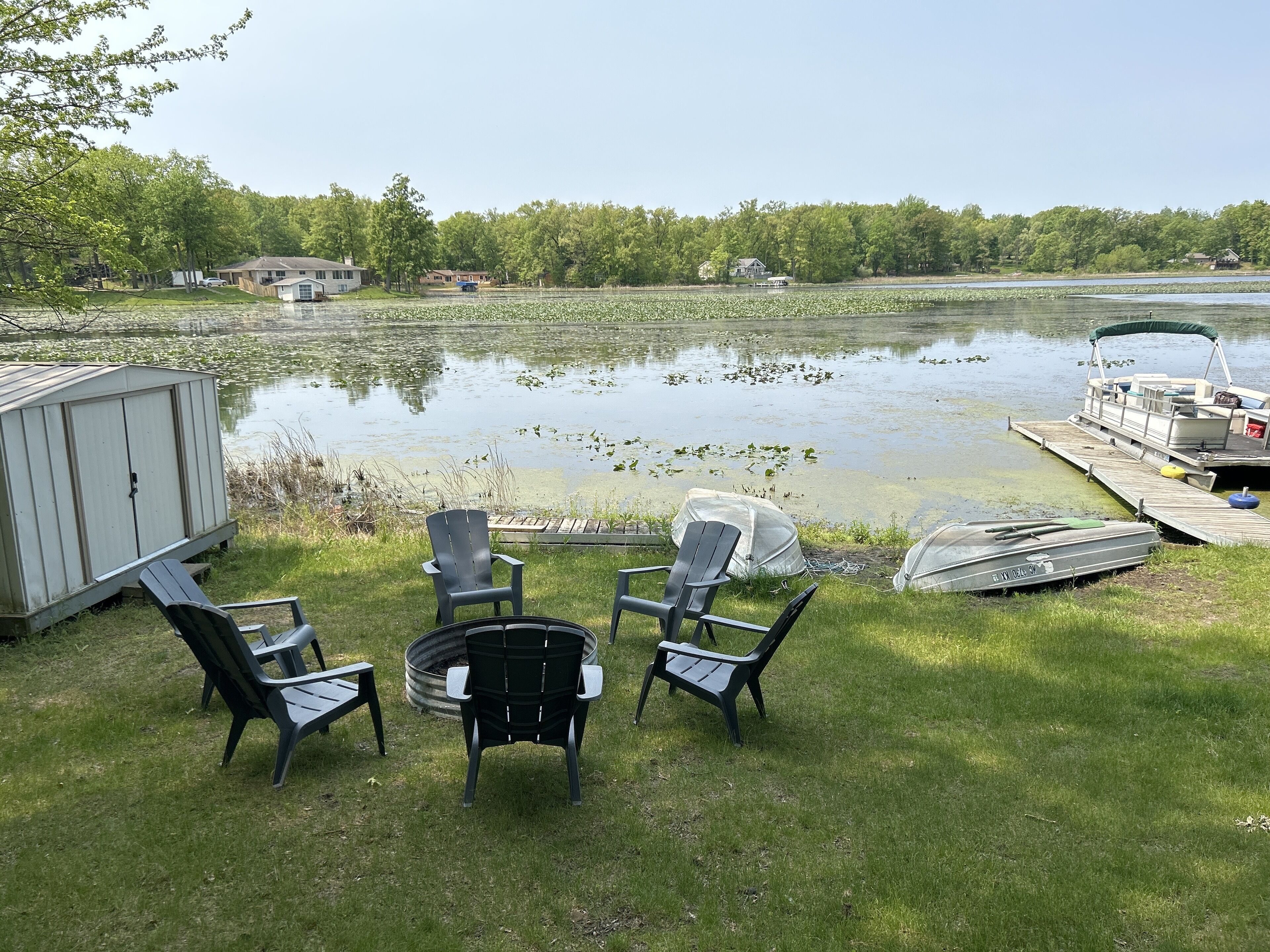 A lakeside deck with outdoor seating, a dock, and a boat.