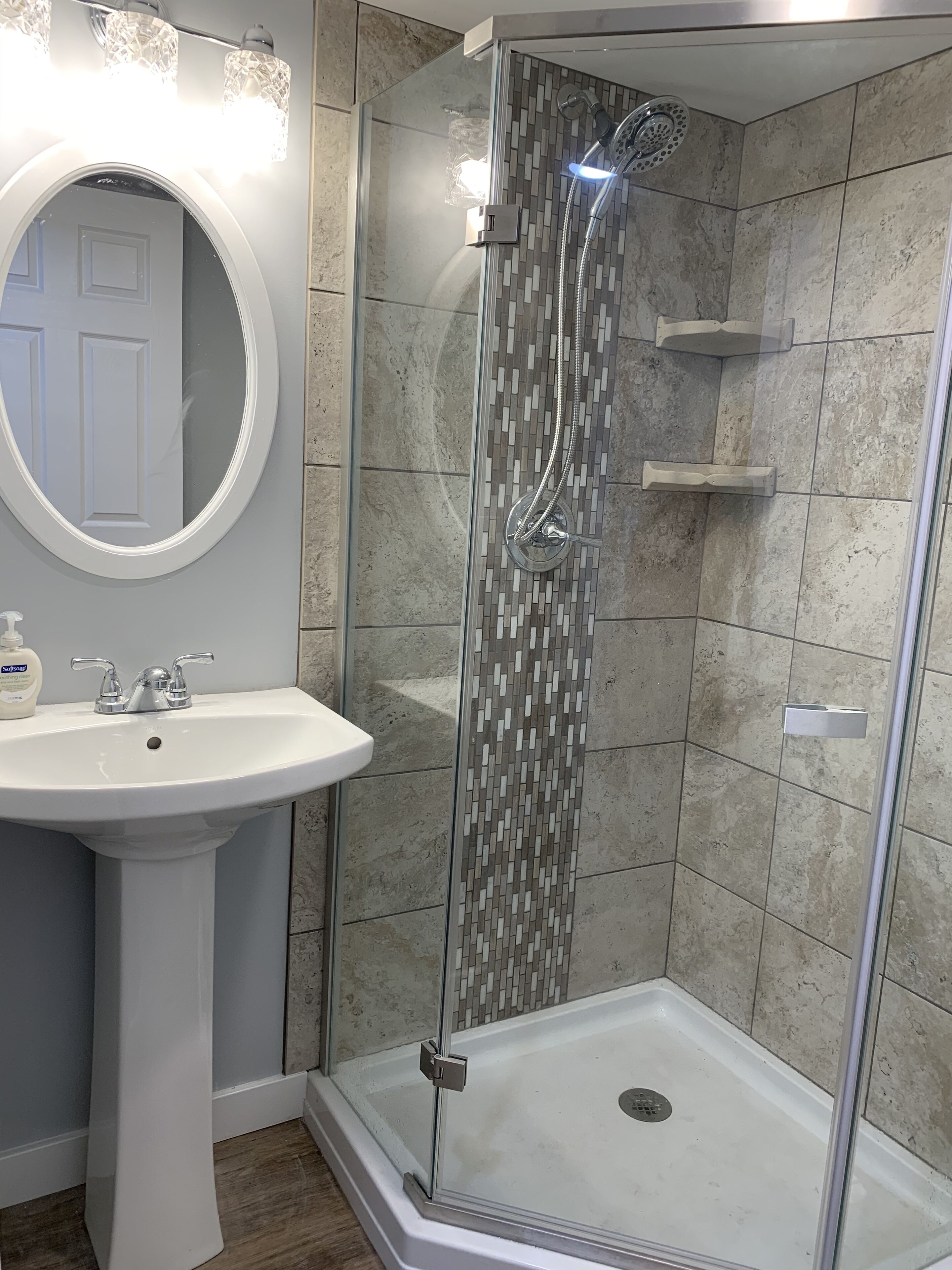 Ein Badezimmer mit Duschkabine, Standwaschbecken und Spiegel.