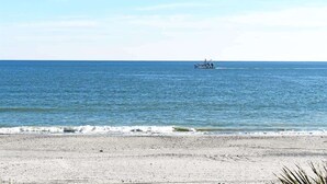 Ein Strand mit einem Boot in der Ferne und wolkenlosem Himmel.