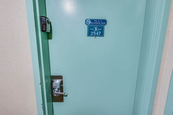 Une porte avec un panneau indiquant qu’il est interdit de fumer, un clavier pour ouvrir la porte et le numéro de chambre : 2547.