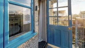 A blue door with a window, a doorbell, and a security camera.