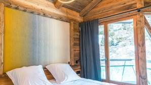 A wooden cabin room with a bed, a window with curtains, and a ceiling with exposed beams and light fixtures. - Top floor Apartment, amazing view, on the slopes ! (Val-d'Isère)