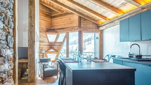 A modern kitchen with a large island, stone walls, and wooden beams. - Top floor Apartment, amazing view, on the slopes ! (Val-d'Isère)