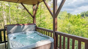 A hot tub on a wooden deck with a view of a forested area. - Property not available (Vilas)