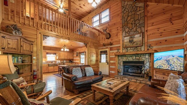 A spacious log cabin interior with a fireplace, wooden furniture, and a balcony. - Property not available (Vilas)