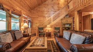 A cozy log cabin interior with leather sofas, a wooden coffee table, and a staircase. - Property not available (Vilas)
