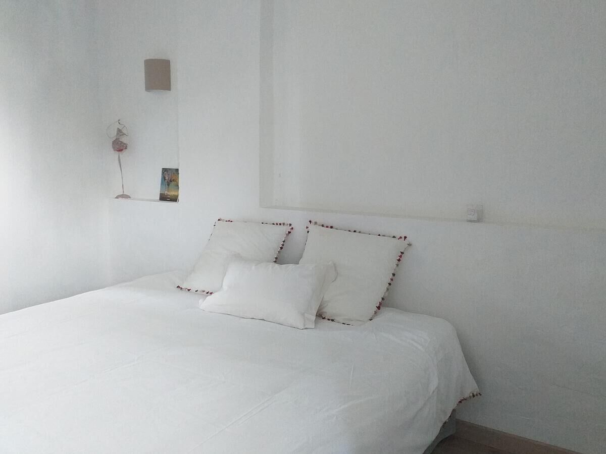 Une chambre simple et épurée, avec un lit simple, du linge de lit blanc et un décor minimaliste.