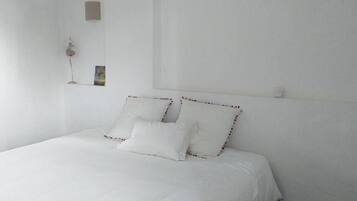 Une chambre simple et épurée, avec un lit simple, du linge de lit blanc et un décor minimaliste.