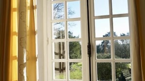 A room with a large window, a radiator below, and a curtain partially drawn. - Ecrin des sens - Manoir en Agenais (Puch-d'Agenais)