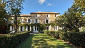 A large, two-story building with a symmetrical facade, a central entrance, and a well-maintained garden with hedges and a lawn. - Ecrin des sens - Manoir en Agenais (Puch-d'Agenais)