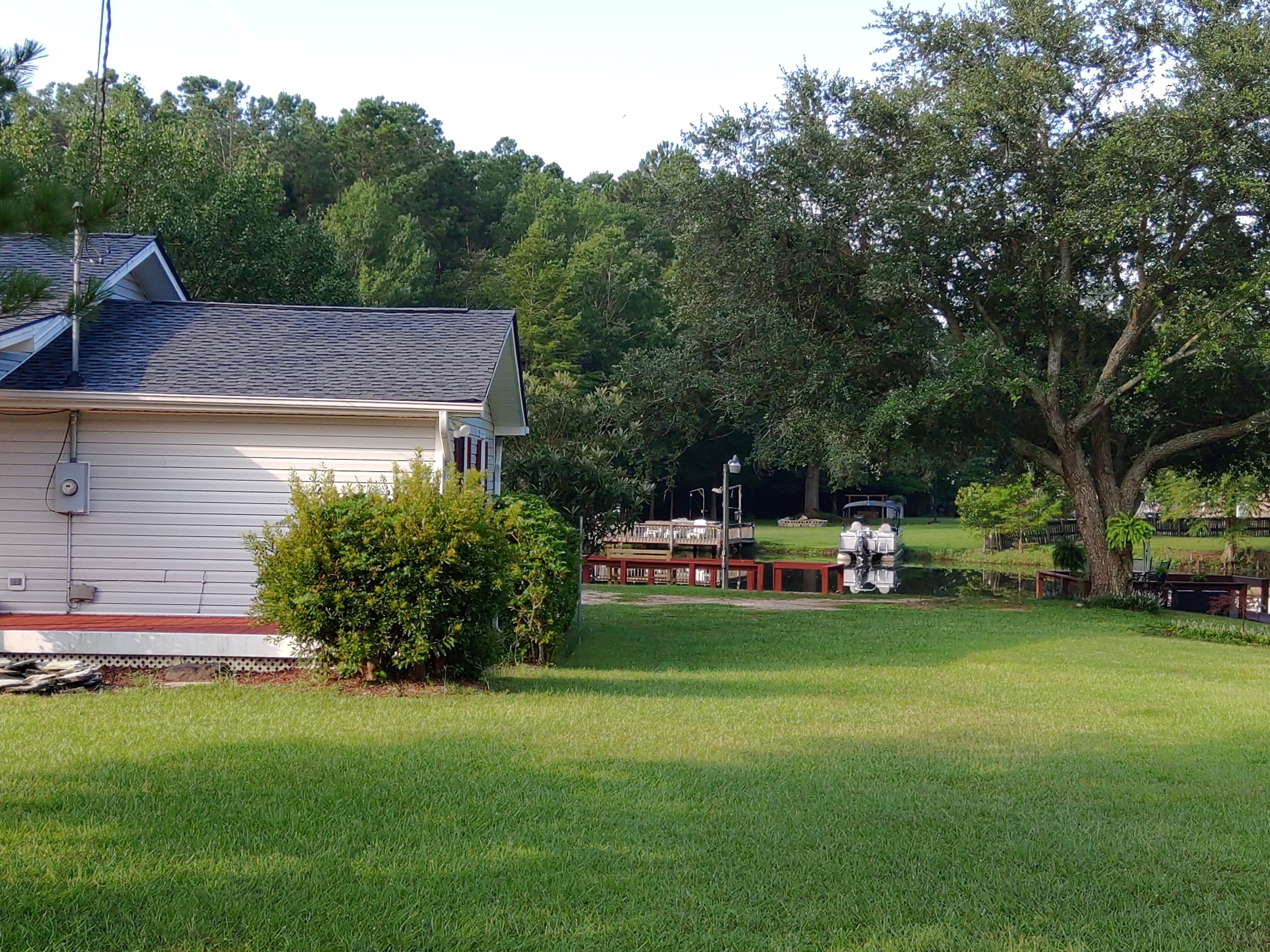 A house with a sloped roof, a small garden, and a dock with a boat.