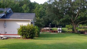 A house with a sloped roof, a small garden, and a dock with a boat.