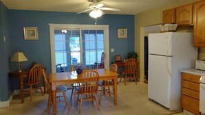 A dining room with a wooden table and chairs, a ceiling fan, and a white refrigerator. - The Lake House at Turtle Cove: Cozy relaxing lake home with dock on wooded lot. (Eutawville)