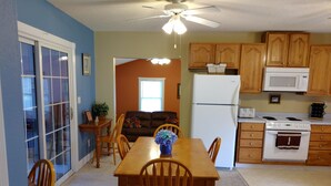 A kitchen with wooden cabinets, a white refrigerator, a stove, and a dining table with chairs. - The Lake House at Turtle Cove: Cozy relaxing lake home with dock on wooded lot. (Eutawville)